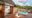 a view of a family bungalow at Etosha-Mountain-Lodge with a small private plunge pool and a small table with water bottle, doors leading into a bedroom featuring a large double bed with mosquito nets,