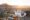 a table with a white cloth set with alcoholic drinks for sundowner drinks, two chairs next to it all set for sunset viewing in the desert