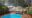 an outdoor pool set around a wooden decking with trees all around it and a lake or a waterhole in front of it