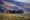 three jeeps parked in a line with a rocky hill behind them and people waiting by them at the base of mount bromo in indonesia