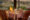 wooden table dressed with a table cloth with pattern, dressed with glasses, lamps, cutlery - all set in the african bush