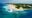 Wild beach peninsula with white sands, further back lush green vegetation and a crystal clear teal blue sea.