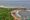 an aerial view of Nosara beach in Costa Rica with a long sandy stretch of the beach curved along the sea and featuring a small town in the distance