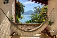 a white hammock hooked between two walls overlooking the ocean and jungle