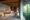 inside of a bungalow at Rio Perdido with large open space, large bedroom with brown throw blanket, two side lamps, coffee table and floor to ceiling window leading onto terrace