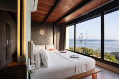 stunnin gsignature suite featuring full wall glass window overlooking the ocean, double bed in the middle