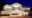 Villa Caemilla Boracay in the philippines a white building with two pointed roofs on one end and on the other side a flat roof over a terrace sits on sand with a night sky and on the sand to the left are black tables and chairs underneath some umbrellas