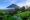a view of a conical volcano under a clear blue sky, partially obscured from view by lush green forest.