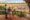 a couple standing on a private wooden terrace looking in to distance where elephants graze on mud and grass