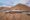 Aerial shot of around 20 1 storey buildings on stilts, nestled on the side of a mountain