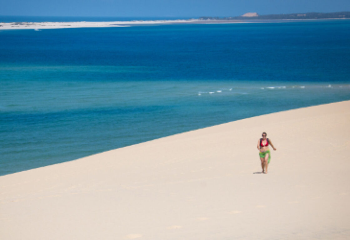a person walking on endless white sandy beach along the ocean
