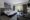a bedroom with large bed, decorative cushions and a throw, armchairs and wall decoration, door leading to a balcony