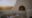a white wall goes down into a bench with a small window in it that has a fire going and opposite is a small table made with a white cloth, wine and cheese and in the distance you can see a sun set over a vineyard