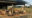 outside of a communal area featuring a few chairs wooden table and a large tent covering the area for shade