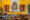 Chanoud Garh in india a yellow wall with a square hole in the wall and two rectangular spaces either side, and a table in front that is laden with spices and vegetables