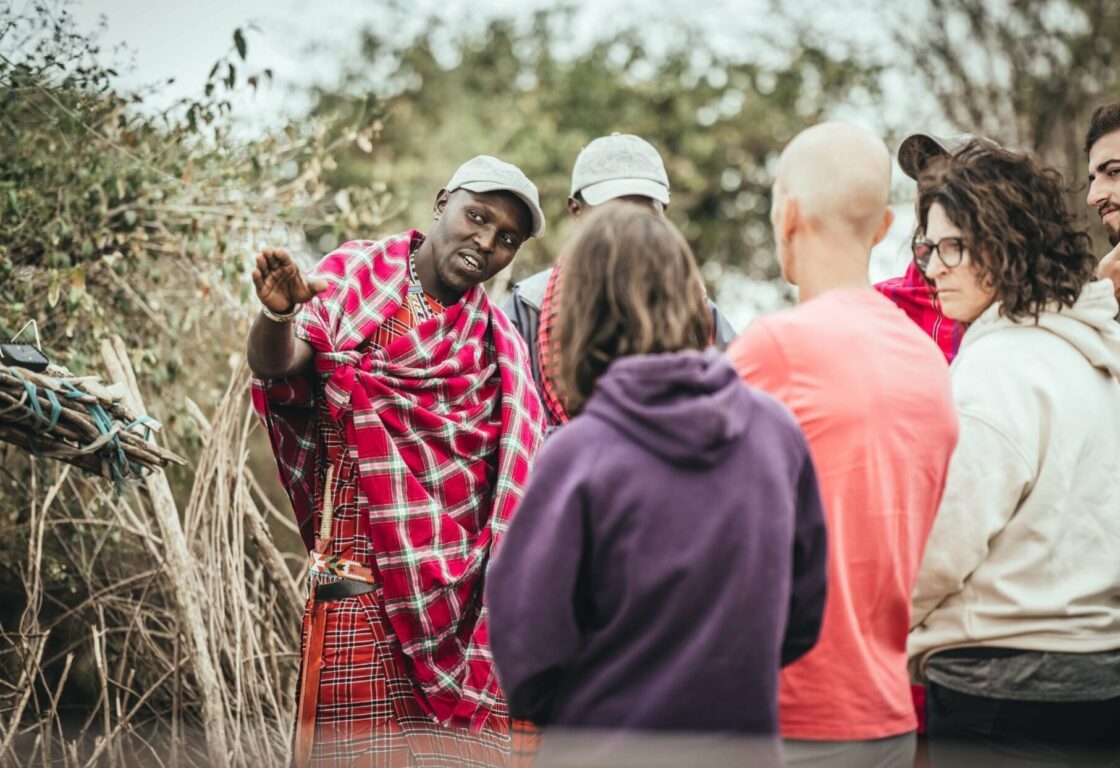 a maasai warrior guide talking to group of people showing them a direction