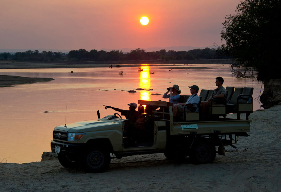 sunset game drive by a lake with people sitting by a lake