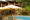 Hotel pool surrounded by jungle plants and deckchairs and umbrellas