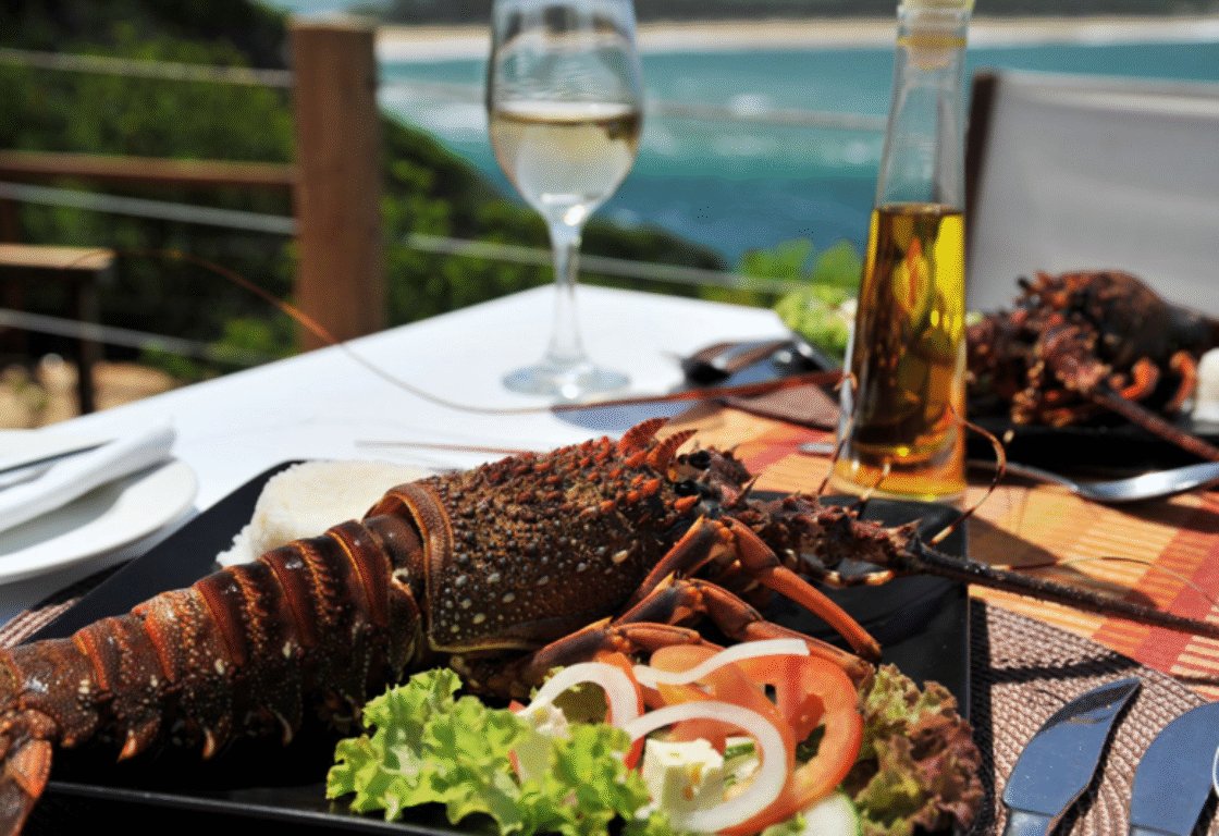 a table with plate with lobster and salad, beer and a glass of wine