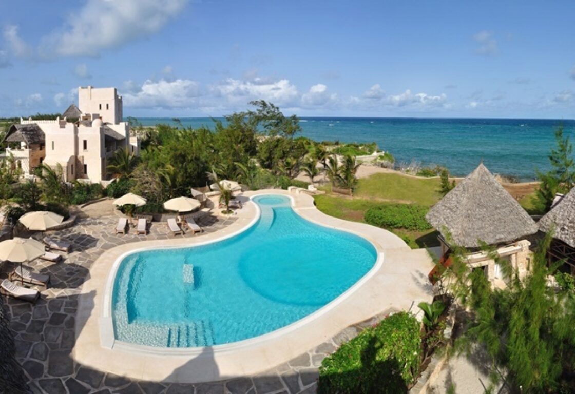 a view of a pool and tached huts around it facing the ocean