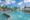 View across the huge expanse of swimming pool at LUX Belle Mare Villas & Suites, ringed by white sun parasols with palm trees reflected in the water.