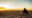 Maasai warrior sitting on the rock overlooking Olduvai plains at sunset