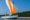 traditional blue boat with orange and white sail sailing on the sea