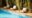a pool area with three white lounge chairs and green wall behind it