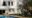 a view of a stylish white building of Mama Ruisa positioned by a pool and with trees and palm trees all around