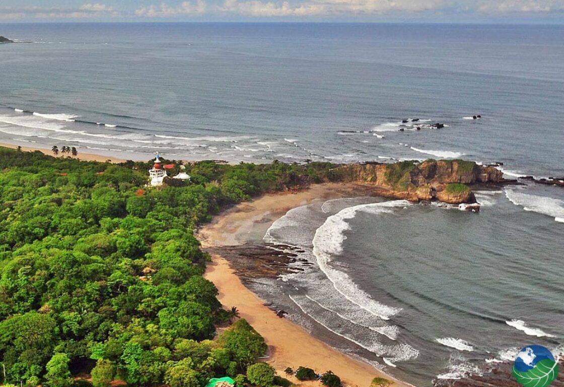 an aerial view of Nosara beach in Costa Rica with a long sandy stretch of the beach curved along the sea and featuring a small town in the distance
