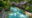 a pool area with lot of green trees and wooden pool bar next to it
