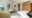 bright bedroom with double bed, a white armchair, wooden wardrobe