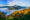 in the distance peaks and hills surround a volcano with clouds all around the base and in the foreground are green hedges at mount bromo in indonesia