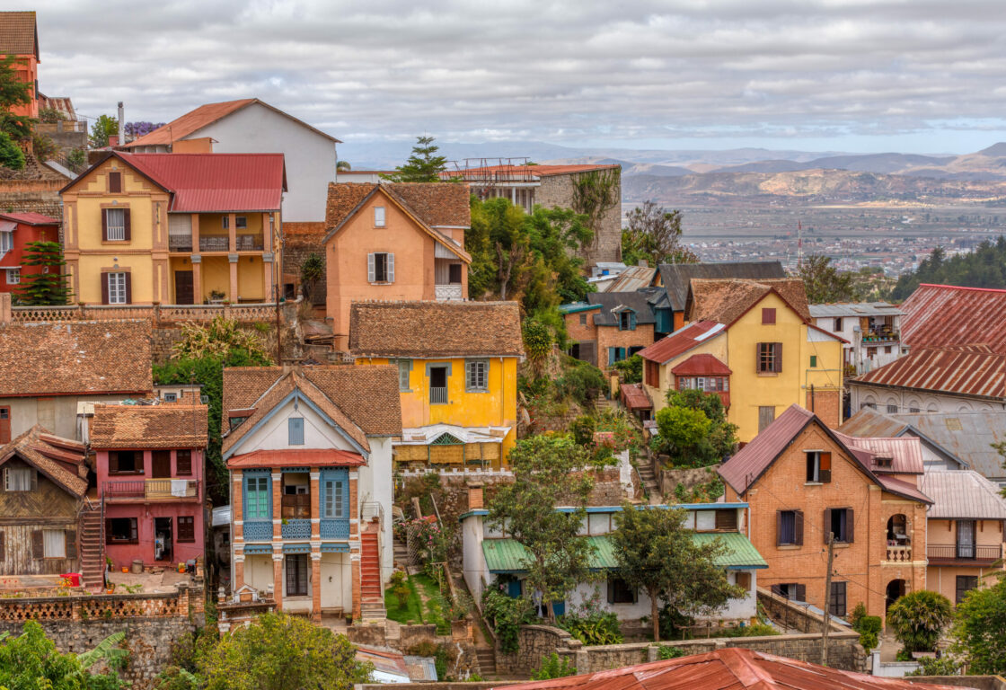 houses of different sizes and styles with varying colours on a hill and in the background a mountain landscape