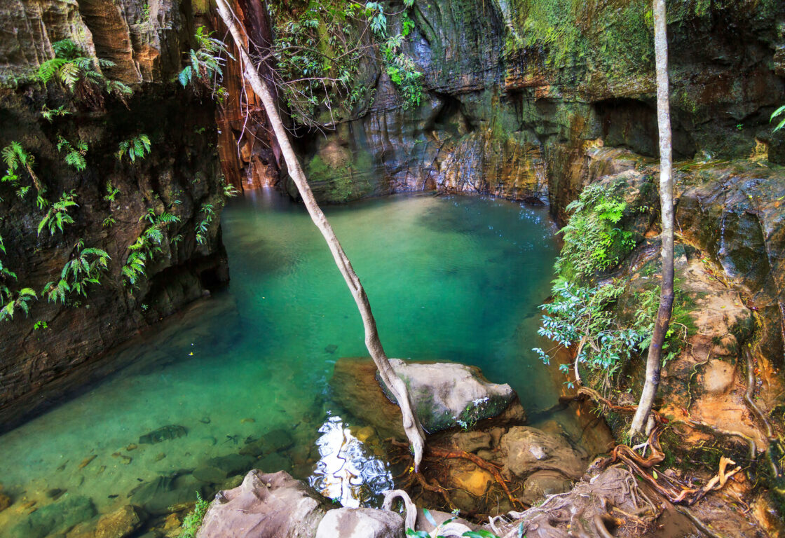 looking down stone cliff walls into a canyon filled with clear blue water in madagascar