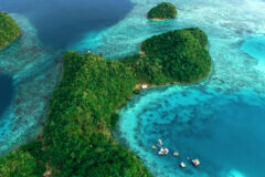 Siargao in the philippines aerial view shows a piece of land bending in a curve and other smaller bits of land off the coast surrounded by the sea and in one corner there is a small cluster of boats