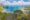 picture taken from a viewpoint in el nido in the philippines that shows jagged limestone cliffs and beyond that is sea in different shades of blue with boats and where the sea meets land there is a cluster of buildings