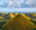symmetrical, grass-covered mounds stretching across the landscape some with pointed tips and some rounded, at the chocolate hills in bohol in the philippines