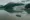 Dramatic aerial image of two csmall cruise ships sailing through a fjord while huge snowy mountains rise up around the water.