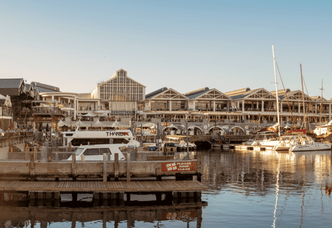a view of a port and boats with historic buildings behind it in Cape Town, South Africa