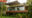 a view of a stand alone bungalow featuring large windows and wooden features