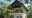 a double bungalow with white walls, tached roof, balcony and terrace located on the beach but around palm trees and trees