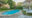 pool area in the garden with stone paving, green trees, lawn and loungers