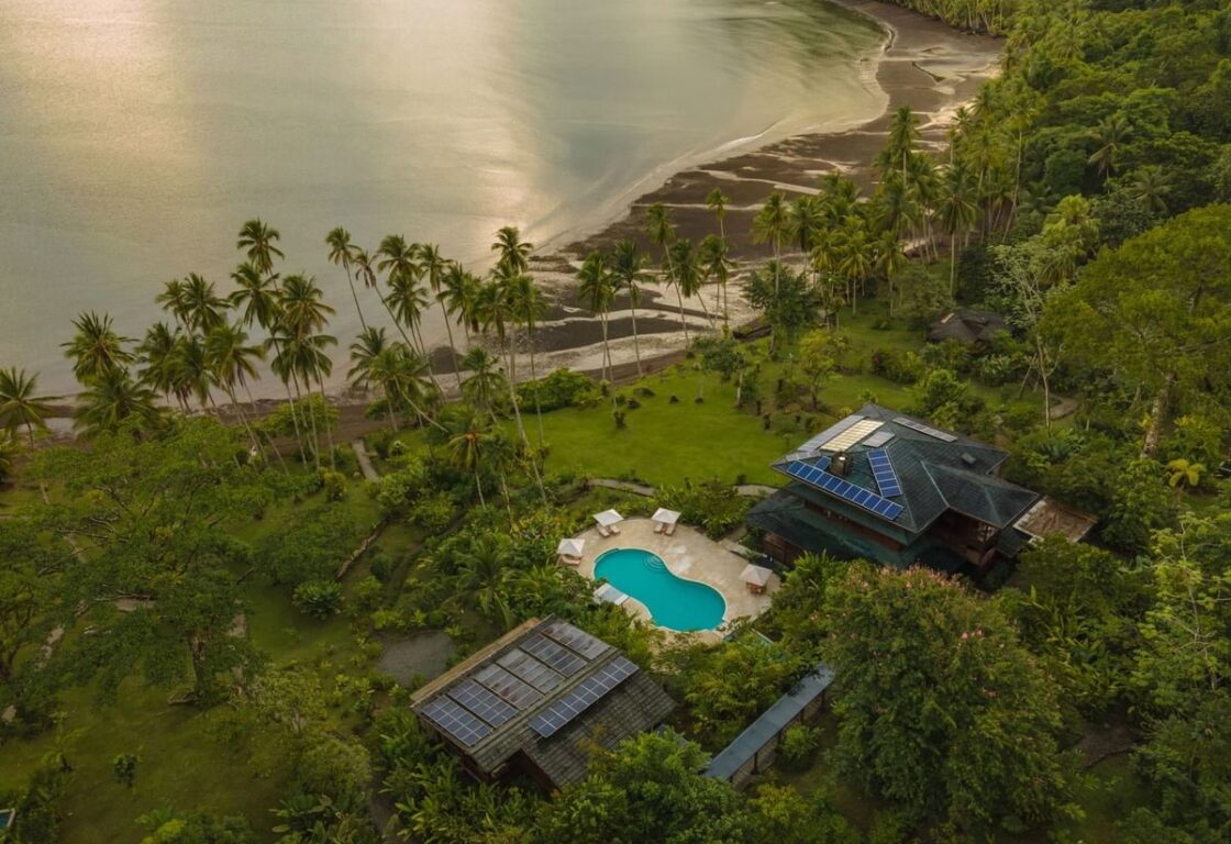an aerial view of a jungle lodge in the middle of a rainforest by the ocean