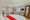 large spacious bedroom with a double bed, red blanket over it, a tv on the wall