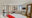 large spacious bedroom with a double bed, red blanket over it, a tv on the wall