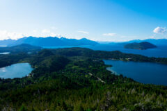 A view of El Trebol Lagoon and Nahuel Huapi Lake under a blue sky, taken from a viewpoint at the top of Cerro Campanario