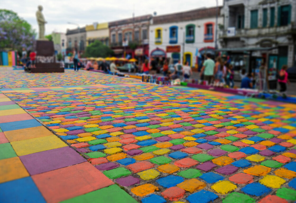 Colourful painted cobblestone street with diners in background, in the Caminito neighbourhood of Buenos Aires
