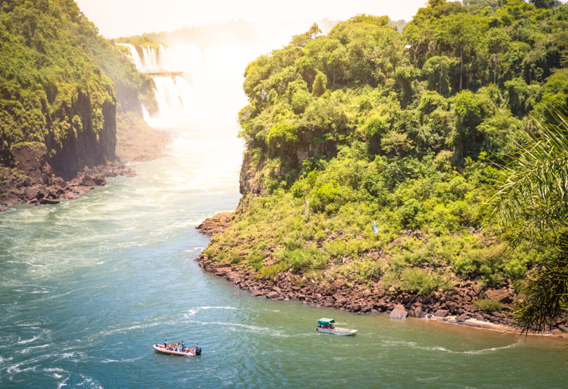 Aerial shot of boats arriving at San Martin Island at Iguazu Falls, with Falls partially visible in the background