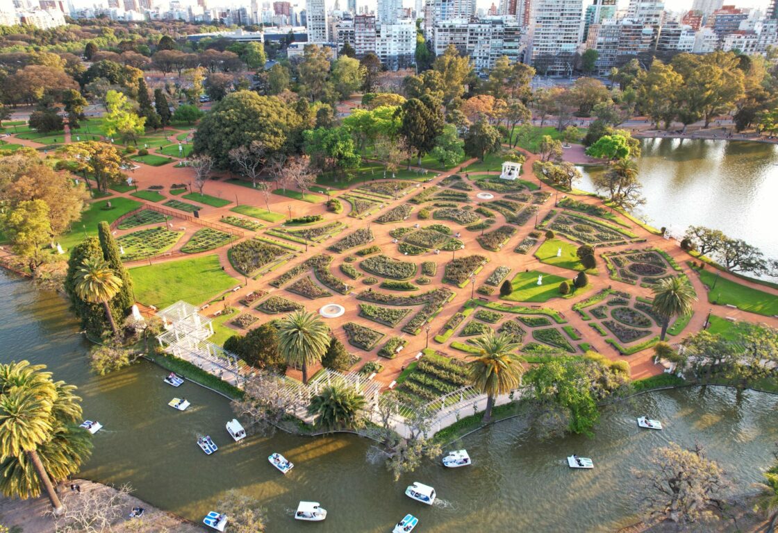 Aerial view of Palermo Park in Buenos Aires, with river and boats in foreground and cityscape behind.